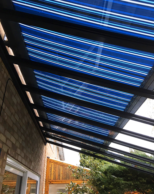 Glass veranda with blue, striped retractable blind